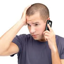 Man grimacing while holding phone to ear Man grimacing while holding phone to ear